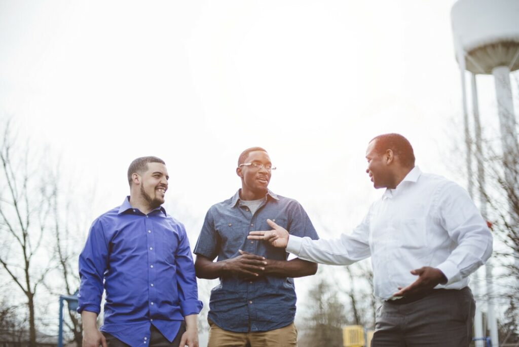 Group of diverse male friends talking to each other and smiling